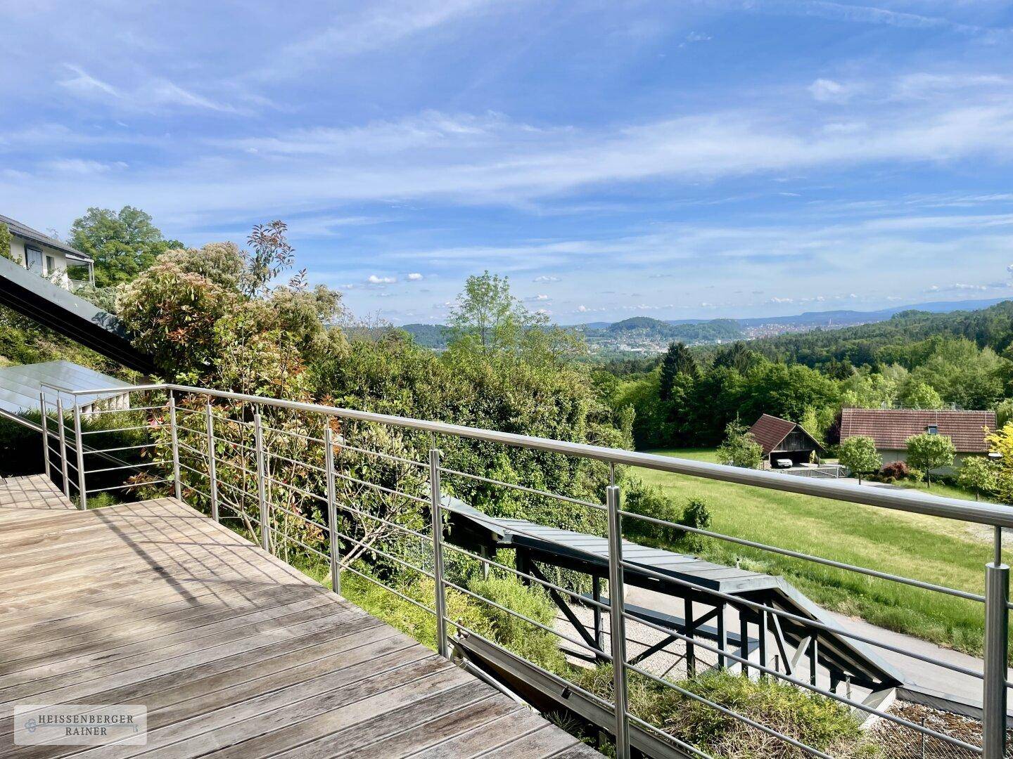 Geräumiger Holzbalkon mit Panoramablick über die Landschaft und eine entfernte Stadt.
