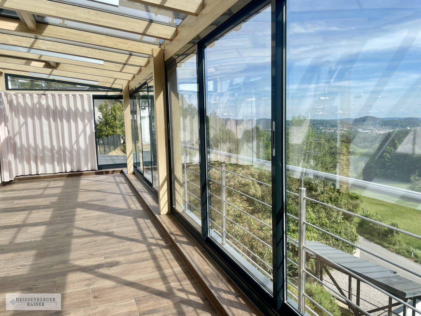 Heller Wintergarten mit großen Glasfronten, Holzkonstruktion und Panoramablick auf die Landschaft.