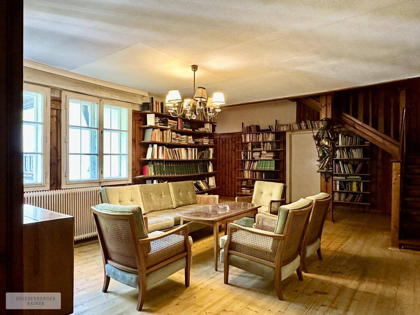 Gemütliche Bibliothek mit umfangreichen Bücherregalen, bequemen Sitzgelegenheiten und Holzboden.