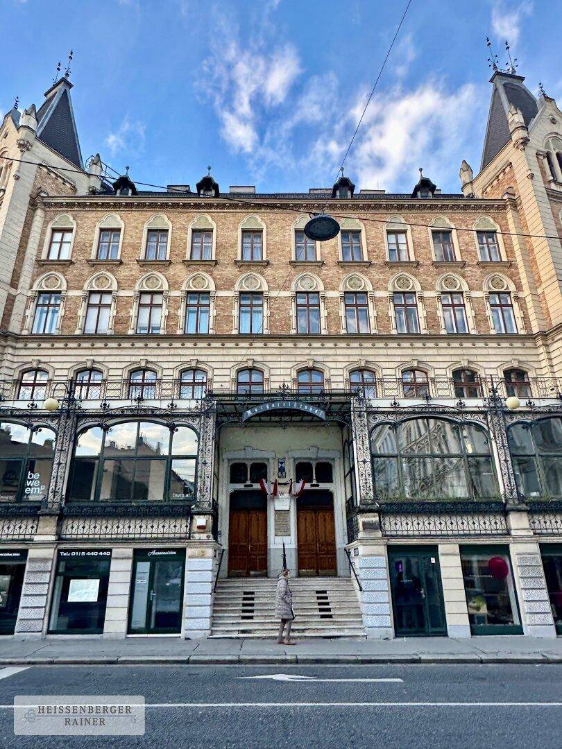 Historische Fassade eines prächtigen Altbaus mit reich verzierten Details und großen Fenstern.