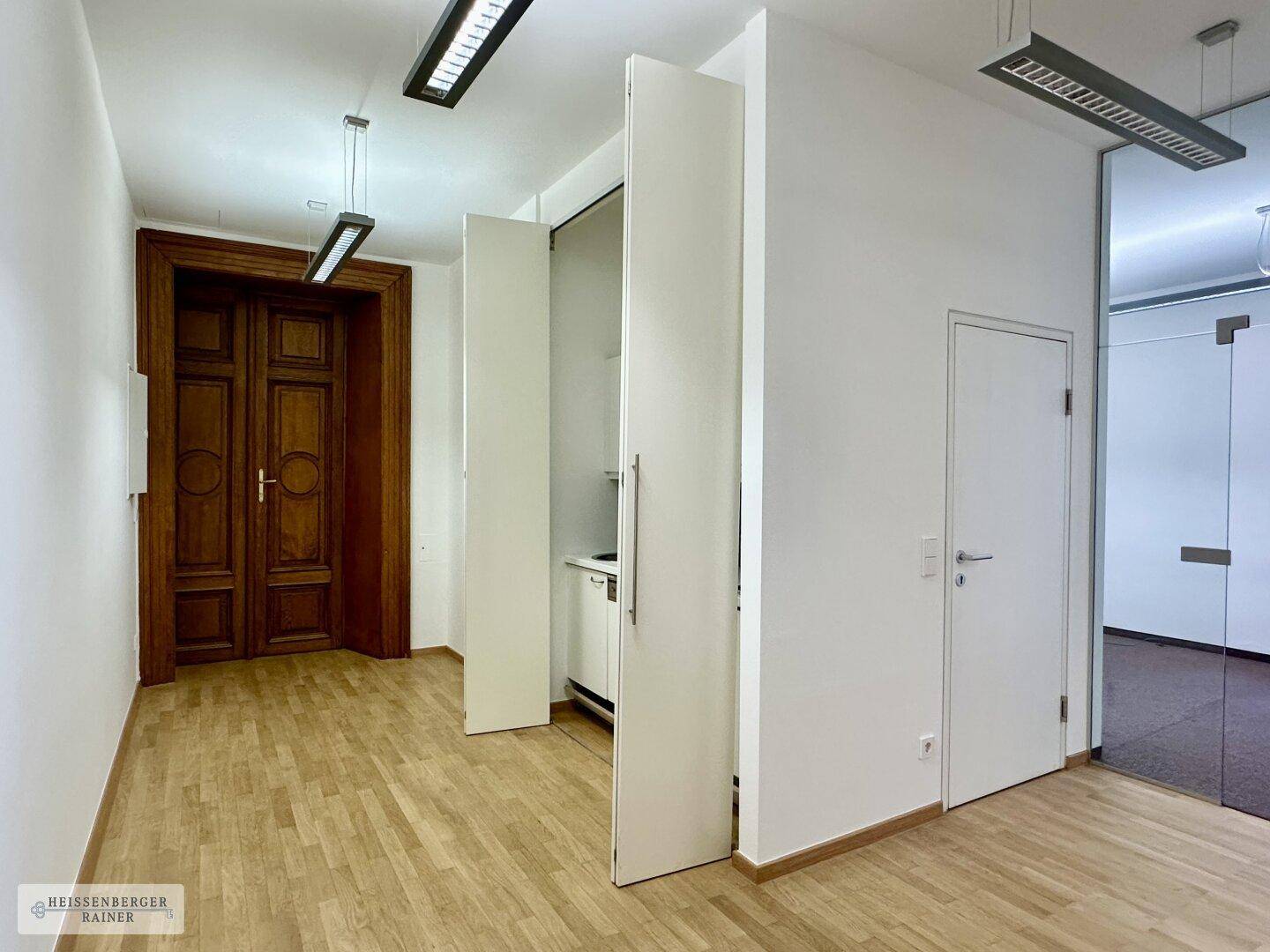 Flur mit Holzboden, versteckter Küchenzeile und einer beeindruckenden Holztür.