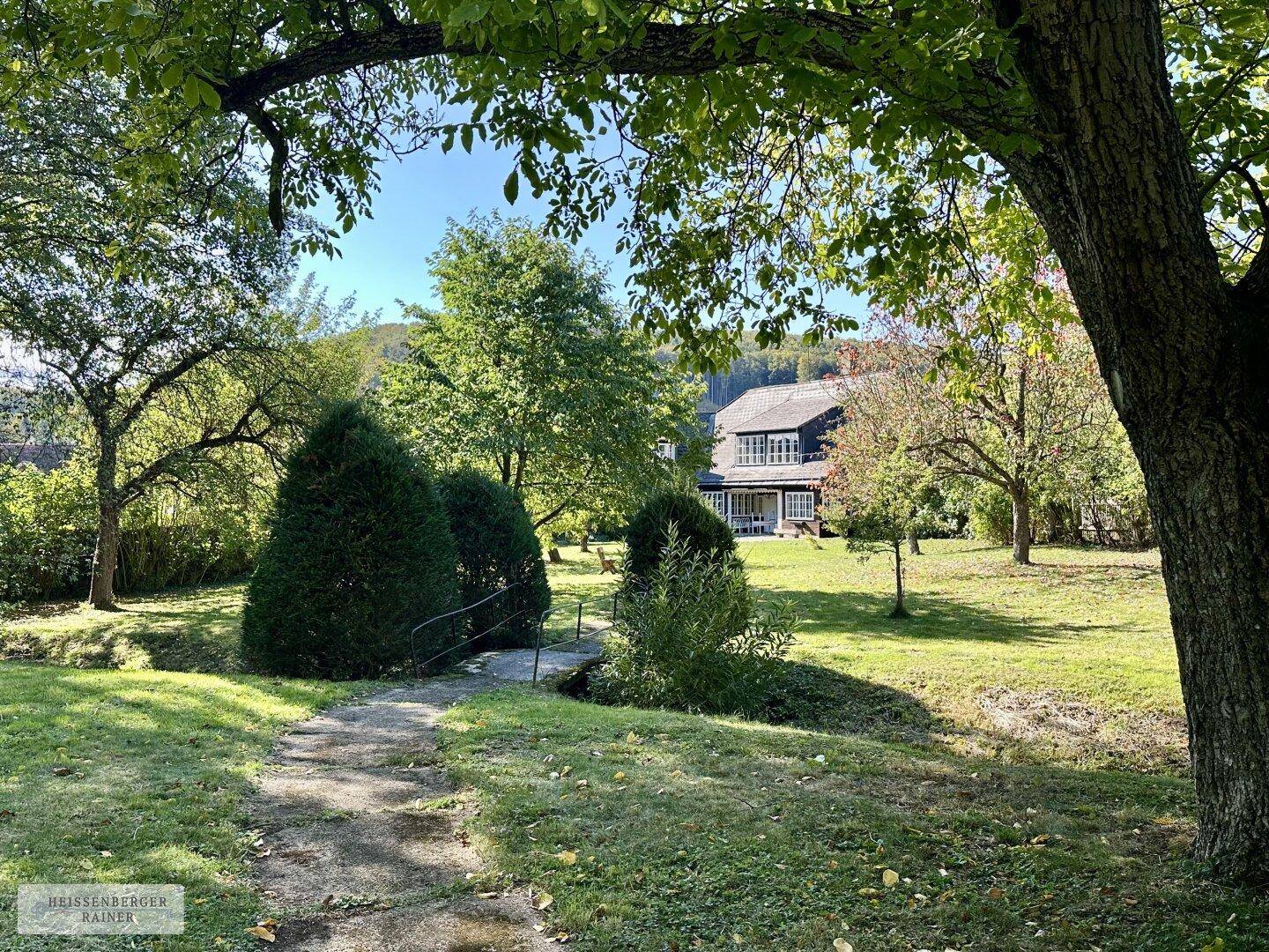 Weitläufiger Garten mit gepflegtem Rasen und Blick auf das traditionelle Wohnhaus in der Ferne.