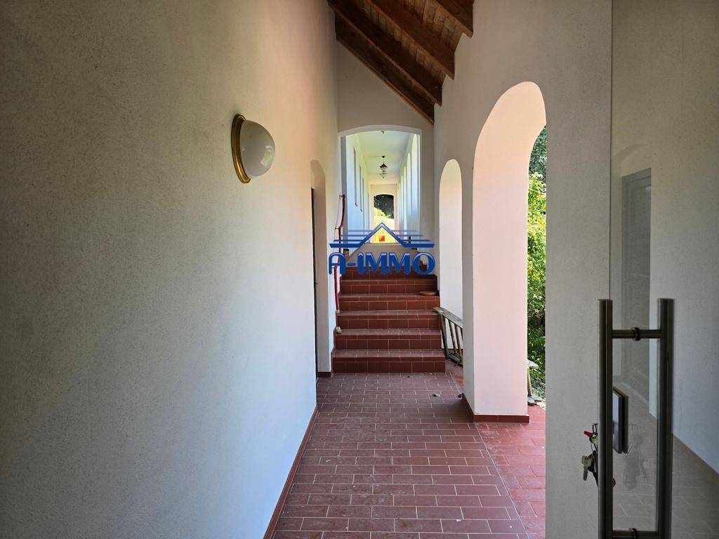 Heller Flur mit Terrakottafliesen, Rundbögen und Treppe zu einem oberen Bereich.