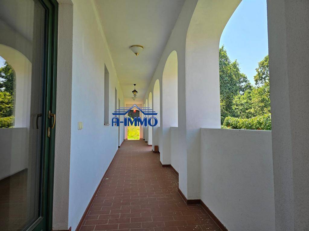 Überdachter Gang mit Rundbögen und Terrakottafliesen, bietet Schutz und Ausblick.