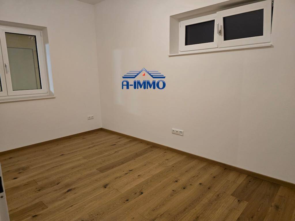 Helles Zimmer mit Holzboden und zwei Fenstern, ideal als Kinder- oder Gästezimmer.