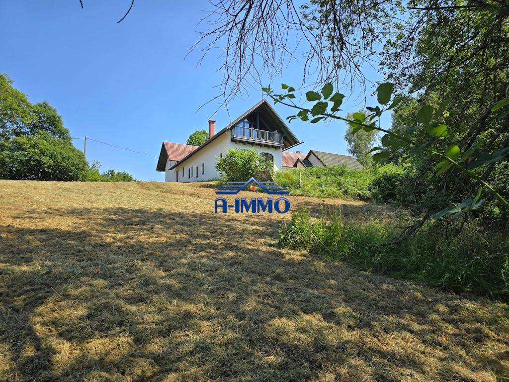 Landhaus mit Balkon im Dachgeschoss und weitem Blick über die grüne Landschaft.