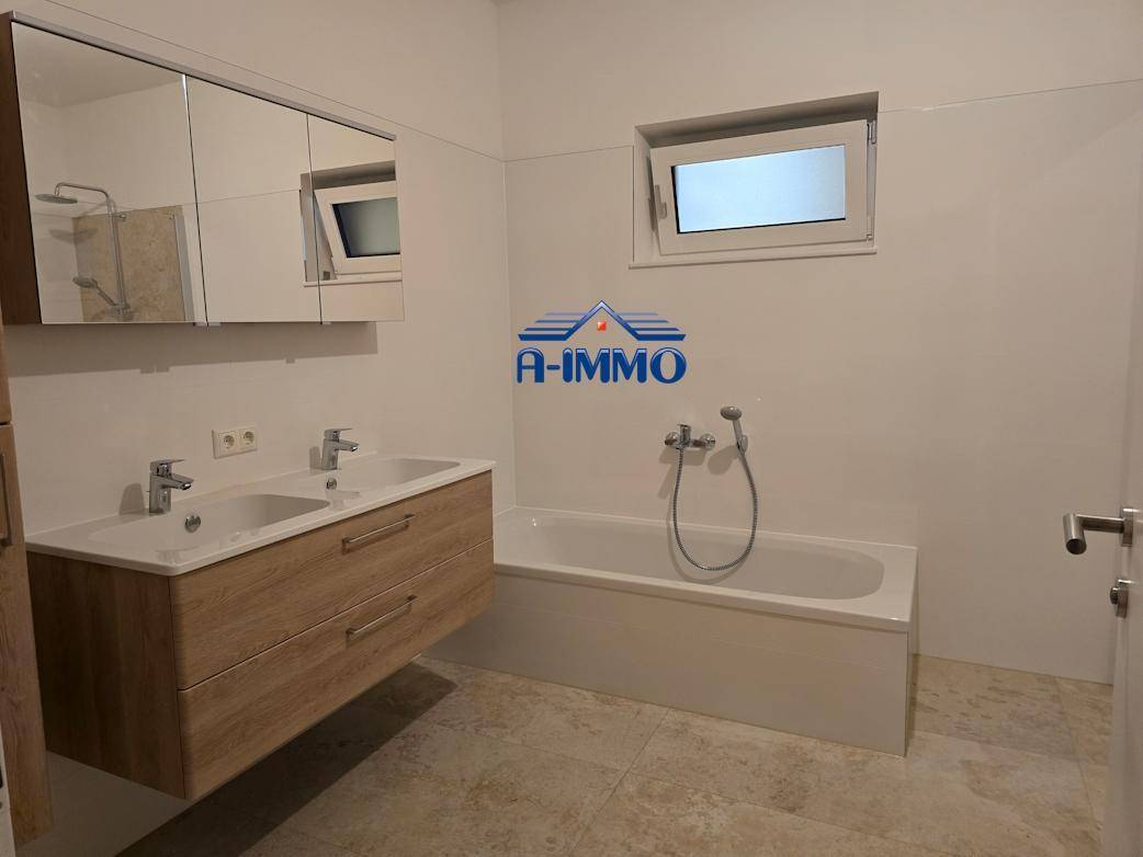 Modernes Badezimmer mit Doppelwaschbecken, Badewanne und Spiegelschrank.