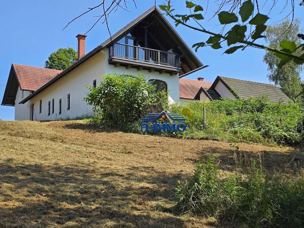 Nahaufnahme des Landhauses mit Balkon und traditionellem Ziegeldach in ländlicher Umgebung.