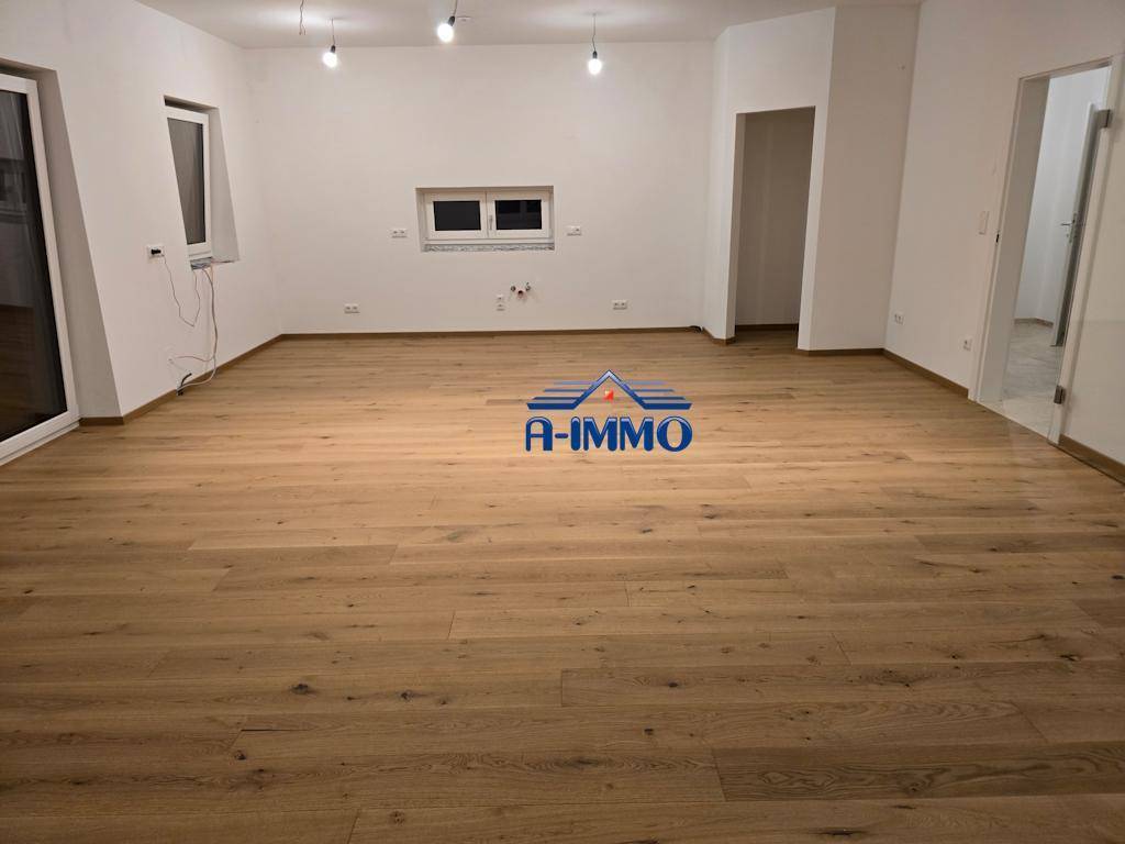 Weitläufiger Wohnbereich mit hellem Holzboden und weißen Wänden, bereit zur individuellen Gestaltung.