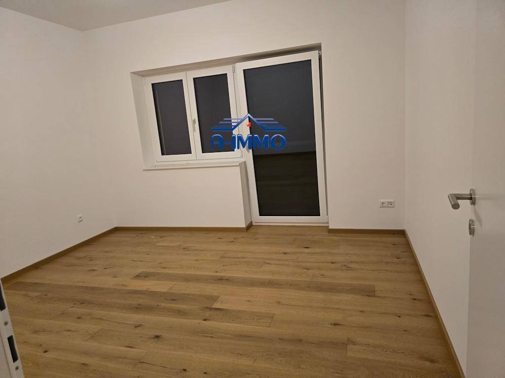 Schlafzimmer mit Holzboden und großem Fenster, das viel Licht in den Raum bringt.