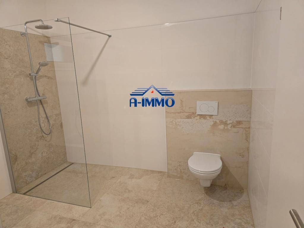 Modernes Badezimmer mit ebenerdiger Dusche und wandhängendem WC, in hellen Farbtönen gehalten.