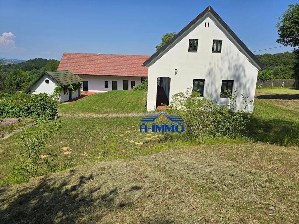 Vorderansicht des Landhauses mit weißer Fassade, grünen Fensterläden und Nebengebäude.