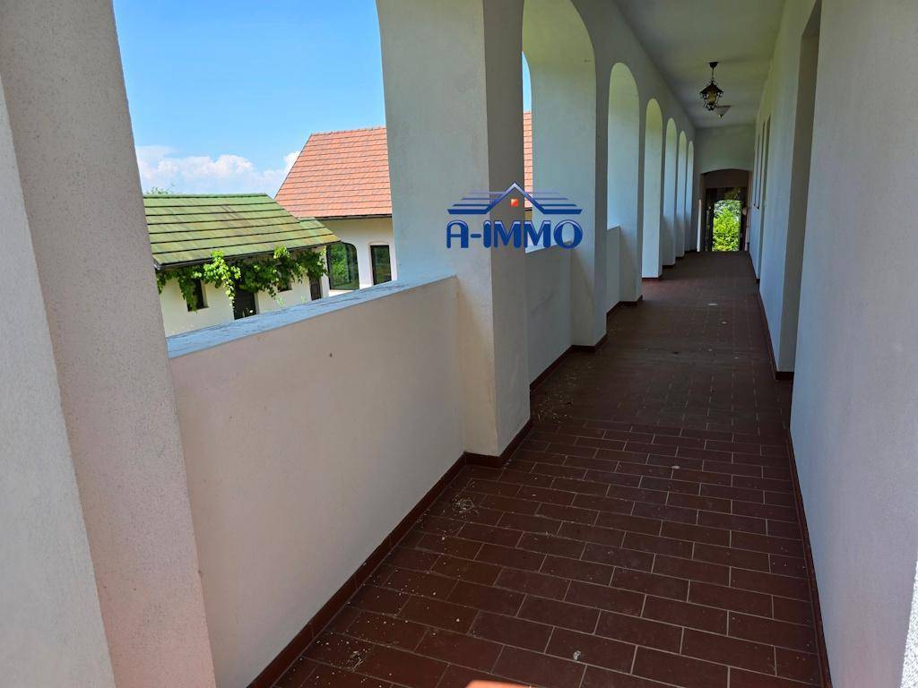 Überdachte Arkade mit Rundbögen und Terrakottafliesen, bietet einen geschützten Außenbereich.