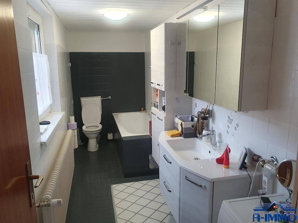 Modernes Badezimmer mit Badewanne, WC, Waschtisch und Spiegelschrank.