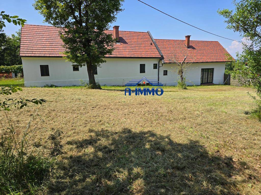 Rückansicht des Landhauses mit rotem Ziegeldach und weitläufigem, sonnigem Rasengrundstück.