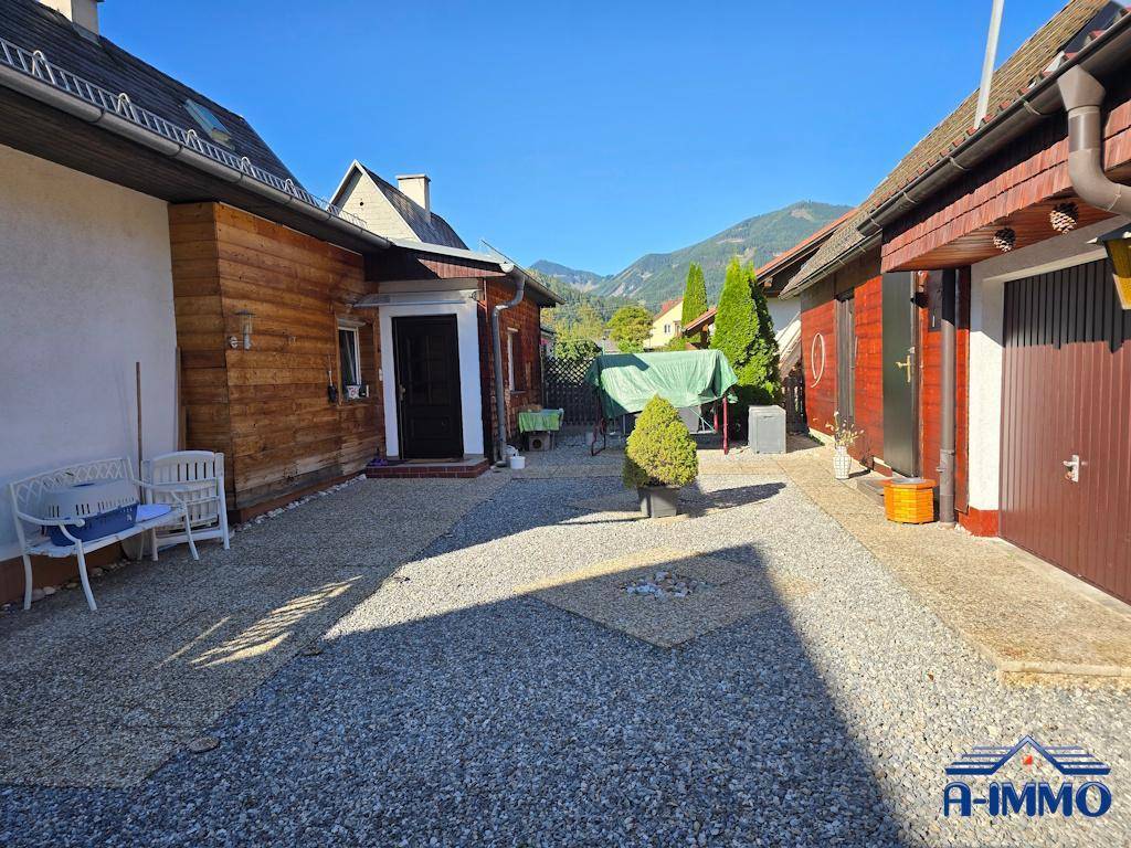 Seitenansicht des Hauses mit Kiesfläche und Bergblick im Hintergrund.