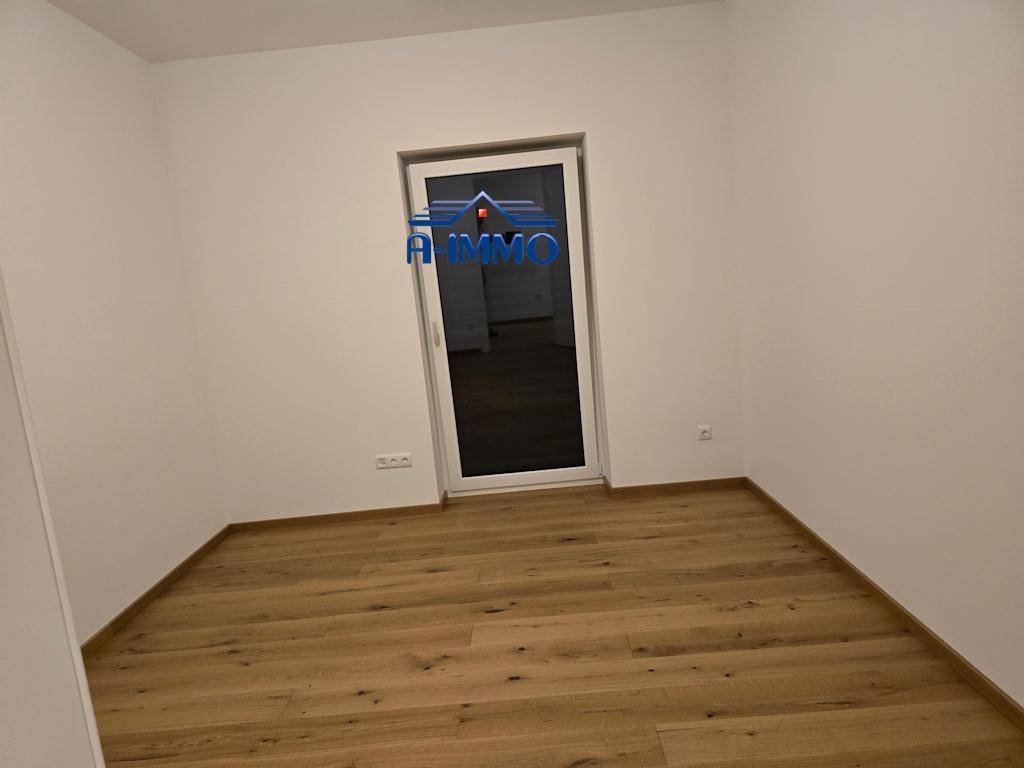 Helles Zimmer mit Holzboden und Tür zum Außenbereich, ideal als Schlaf- oder Arbeitszimmer.