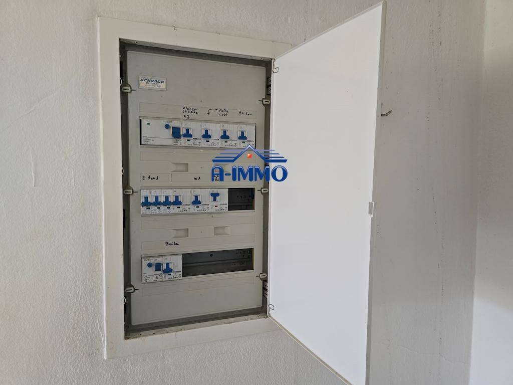 Offener Sicherungskasten an einer weißen Wand, zeigt die elektrische Installation.