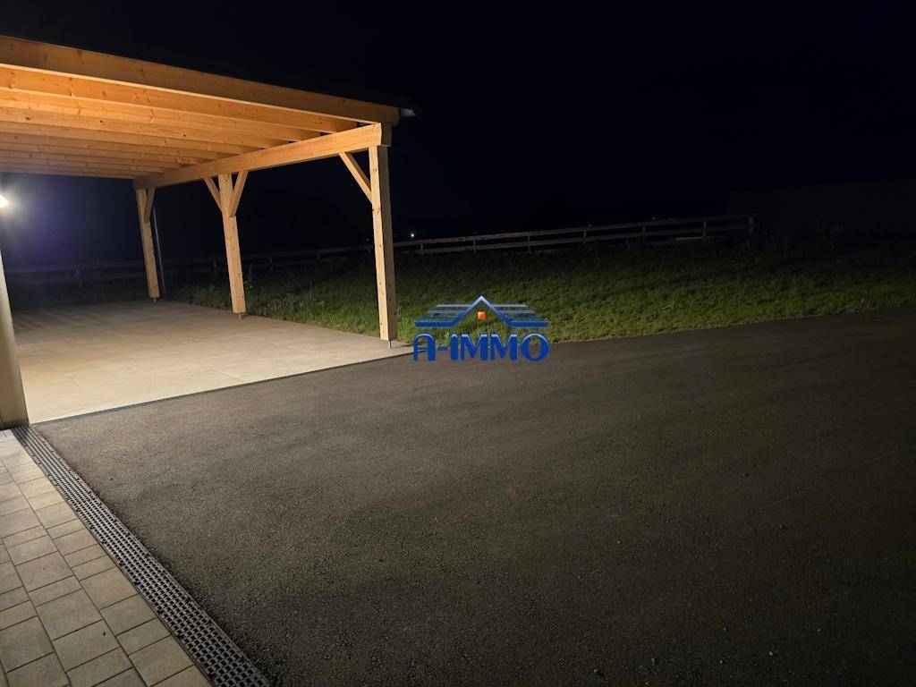 Zufahrt zum Haus mit gepflastertem Bereich und Carport bei Nacht.