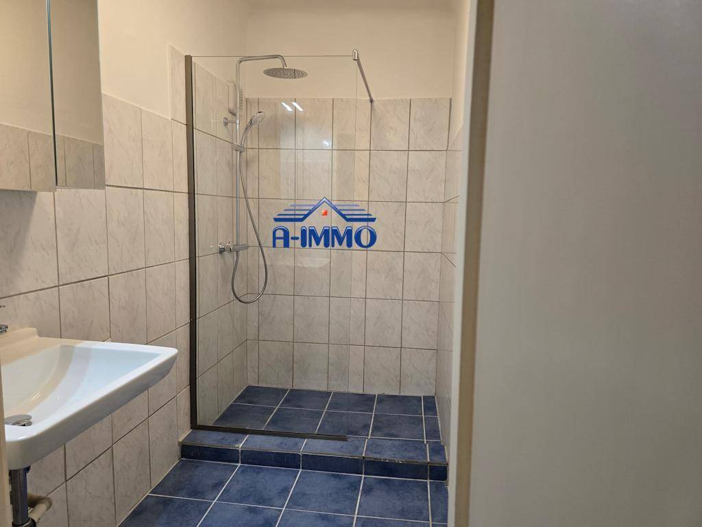 Modernes Badezimmer mit Duschkabine, Waschbecken und hellen Fliesen an den Wänden.