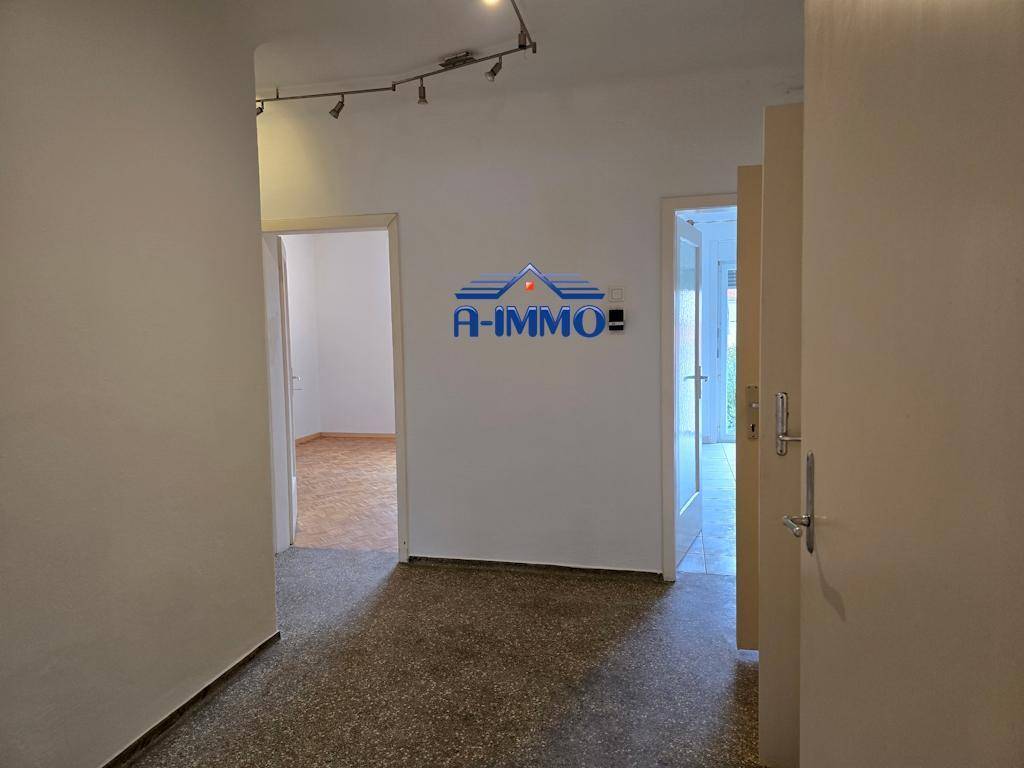 Heller Flur mit Terrazzoboden, der zu verschiedenen Zimmern der Wohnung führt.