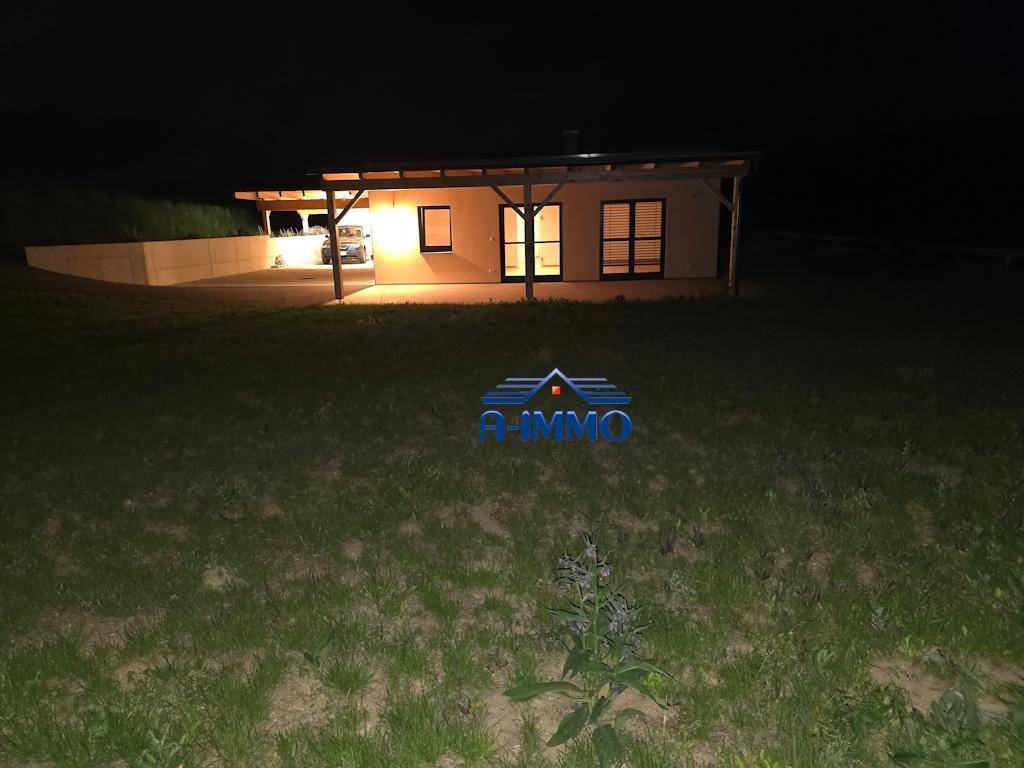 Frontansicht des Hauses bei Nacht mit beleuchtetem Eingangsbereich und Carport.