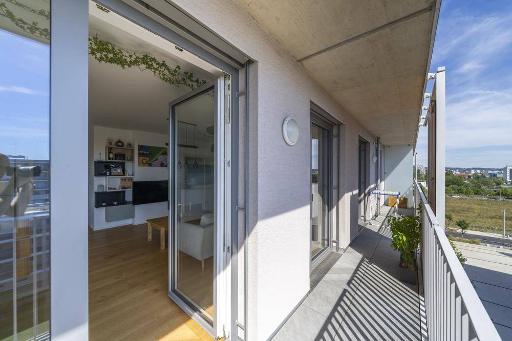 Blick vom Balkon in den hellen Wohnbereich, der eine nahtlose Verbindung schafft.