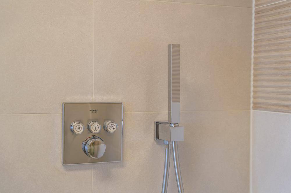 Detailaufnahme einer modernen Duscharmatur mit stilvollen Bedienelementen an der Wand.