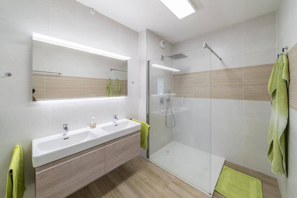 Modernes Badezimmer mit Doppelwaschbecken, großem Spiegel und begehbarer Dusche.