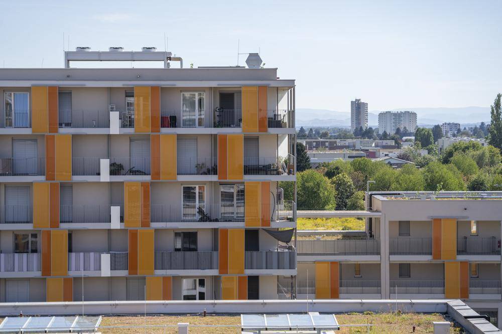 Moderne Wohngebäude mit farbigen Akzenten, Balkonen und Solaranlagen auf dem Dach.
