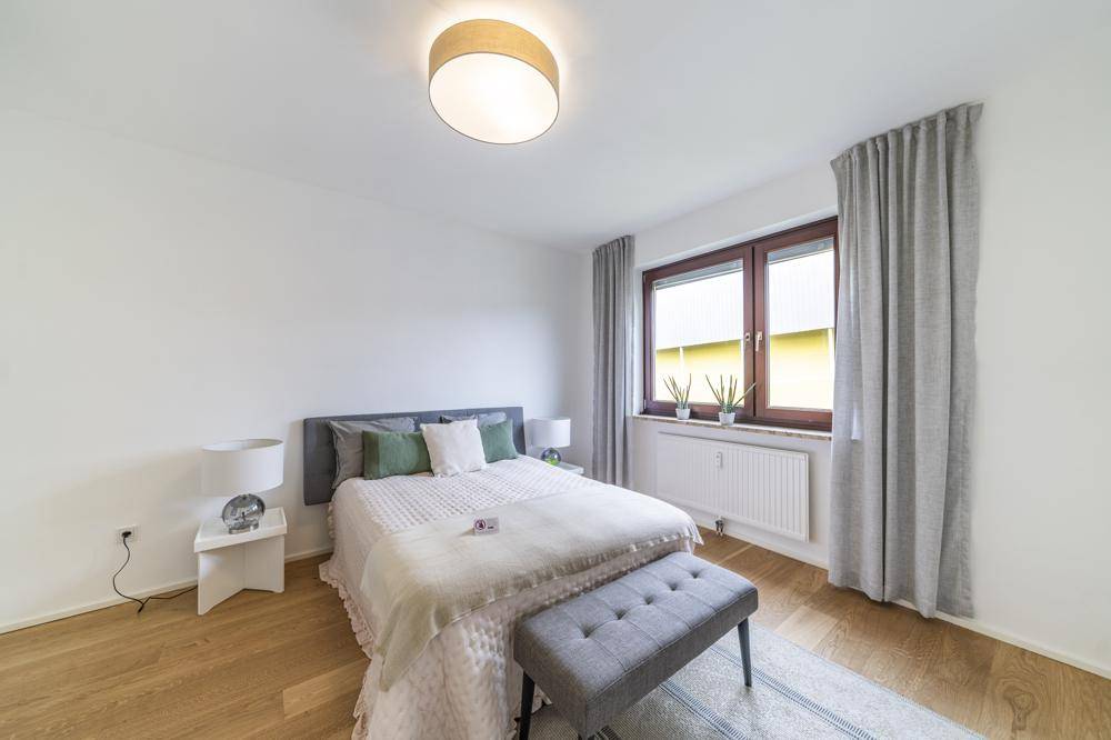 Gemütliches Schlafzimmer mit Doppelbett, Holzboden und Fenster für natürliches Licht.