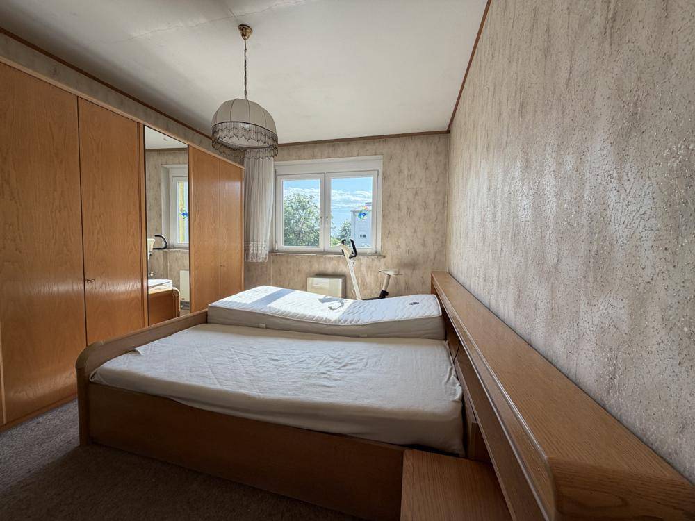 Schlafzimmer mit zwei Betten, Holzschrank und Tapeten, bietet eine ruhige und funktionale Atmosphäre.