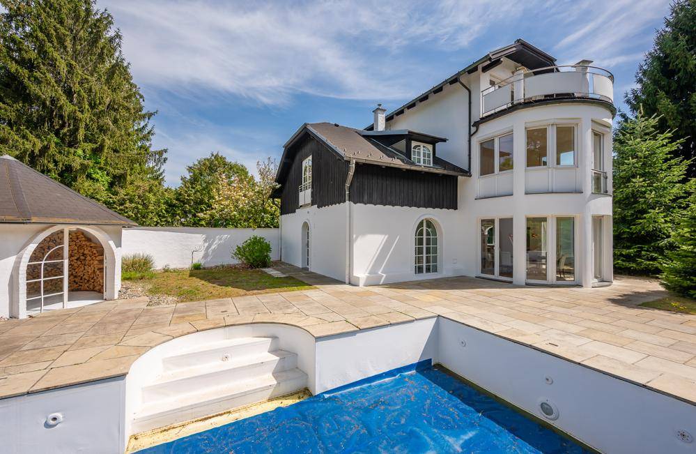 Geräumige Steinterrasse mit Pool und einem Holzschuppen im Hintergrund.