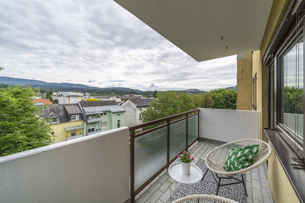 Gemütlicher Balkon mit Sitzgelegenheiten und weitem Blick über die Stadt und die Berge.