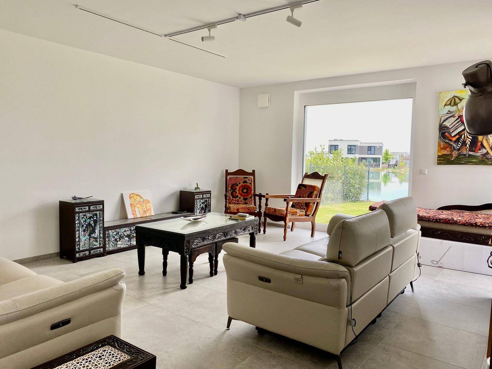Helles Wohnzimmer mit bequemen Sofas, einem Couchtisch und Blick auf den See und moderne Häuser.