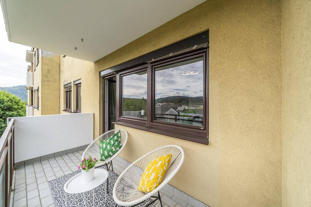 Balkon mit Fliesenboden und Blick auf die Umgebung, umgeben von einer gelben Fassade.