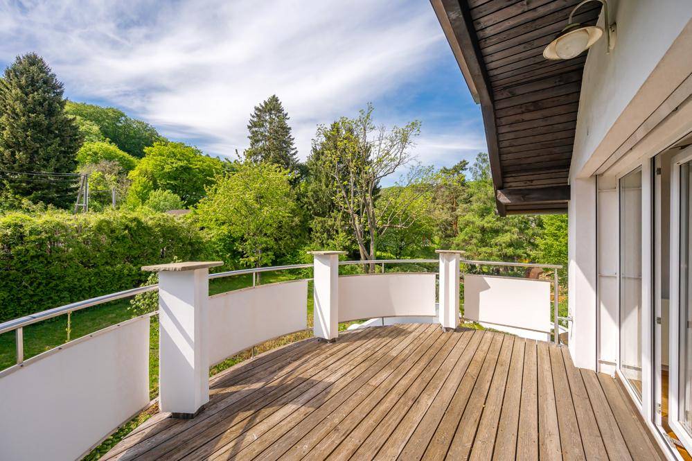 Großer Holzbalkon mit Metallgeländer und weitem Blick ins Grüne.