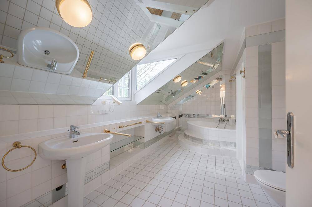 Helles Badezimmer mit Badewanne, zwei Waschbecken und Spiegelflächen.