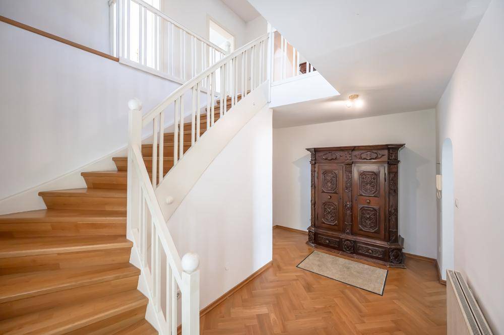 Geräumiger Flur mit Holztreppe und antikem Schrank, der die Etagen verbindet.