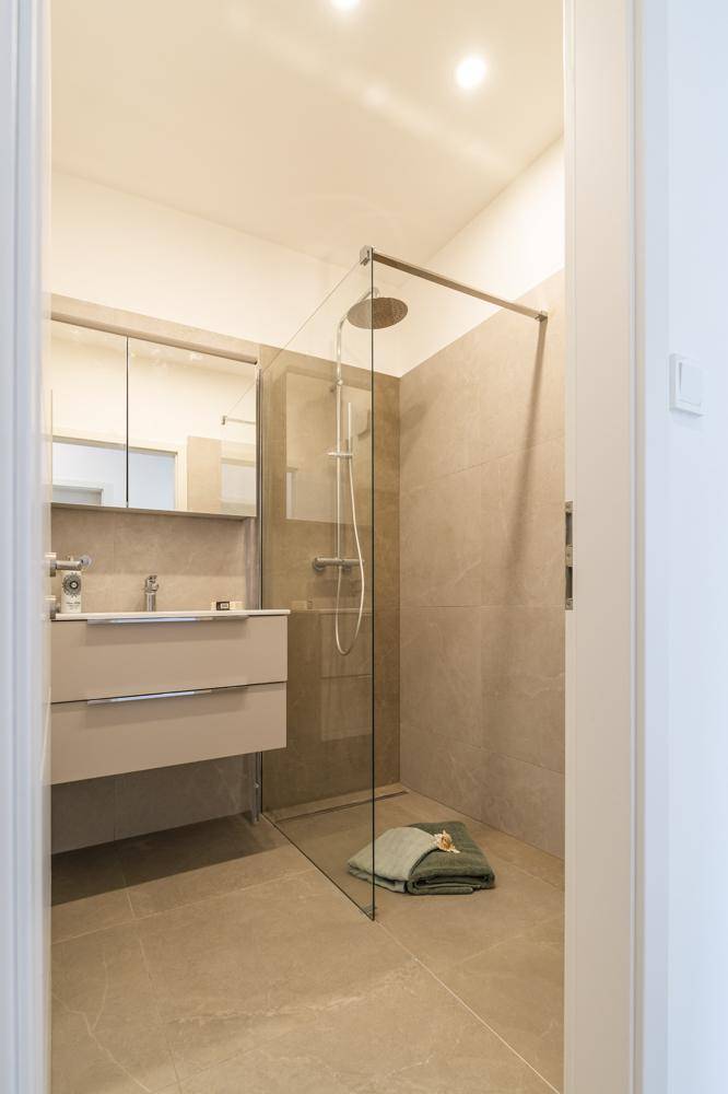 Modernes Badezimmer mit ebenerdiger Dusche, Waschtisch und Spiegelschrank.