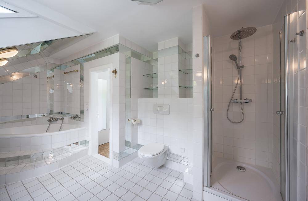 Modernes Badezimmer mit Dusche, WC und weißen Fliesen.