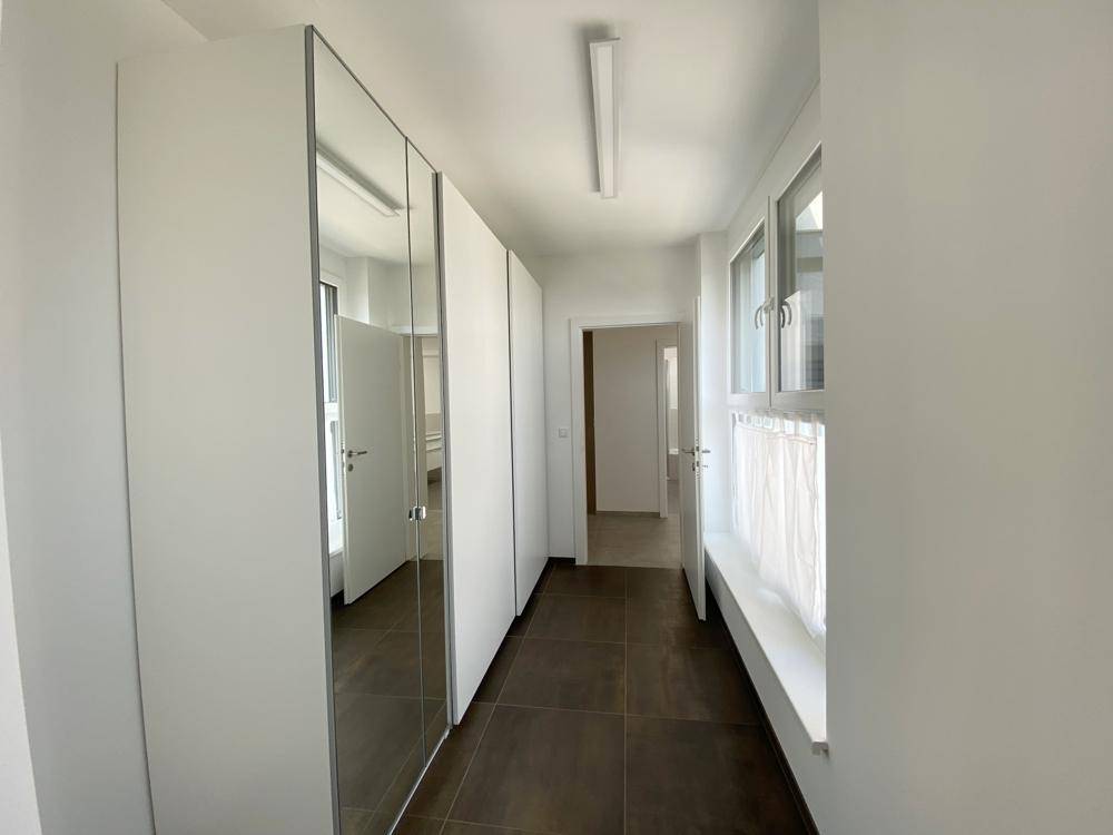 Heller Flur mit Spiegelschränken, Fliesenboden und Fenstern für natürliches Licht.