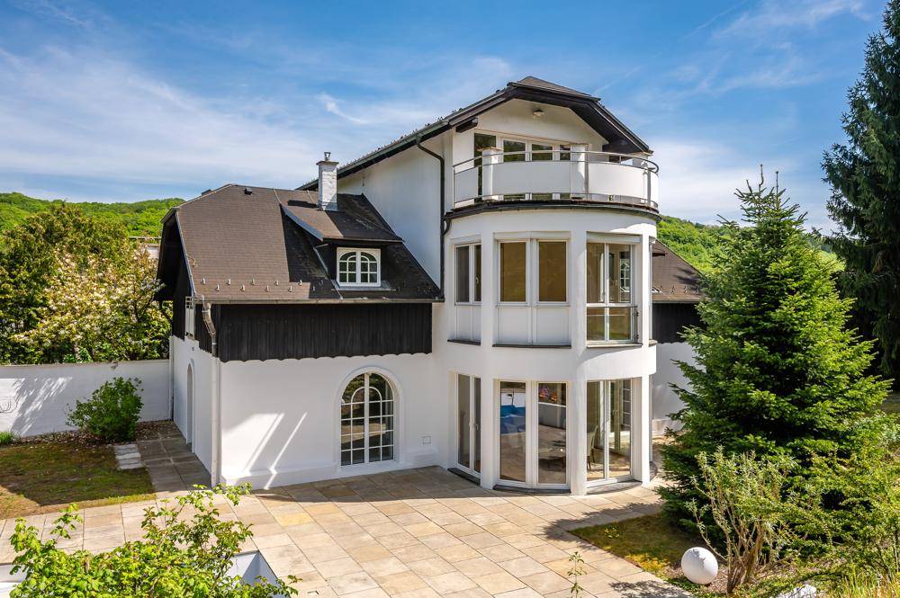 Die weiße Villa mit großer gepflasterter Terrasse und Zugang zum Garten.