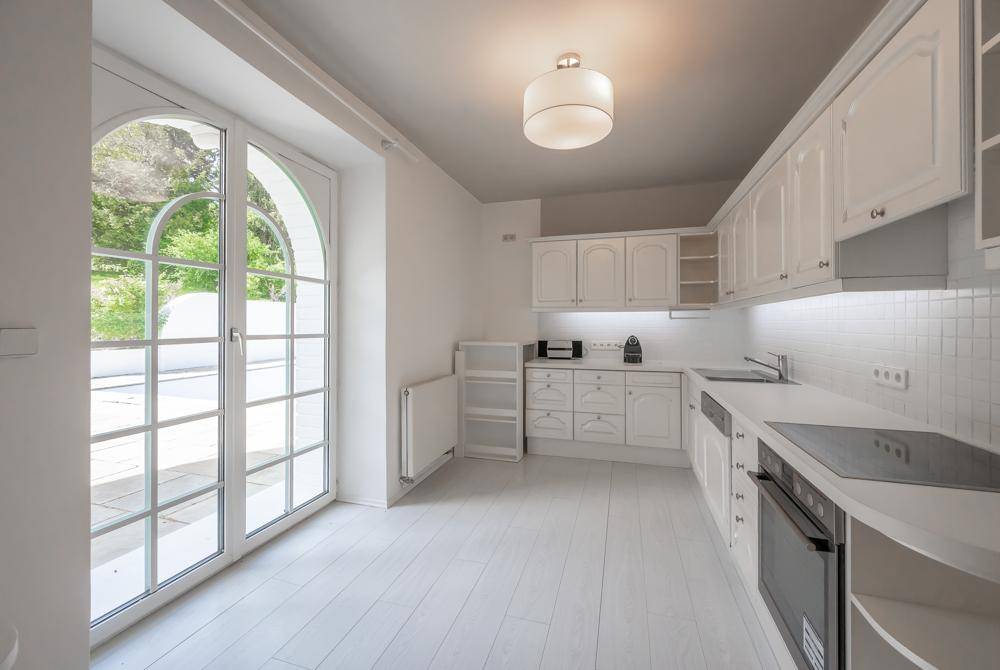 Helle Küche mit weißen Schränken, modernen Geräten und Zugang zur Terrasse.