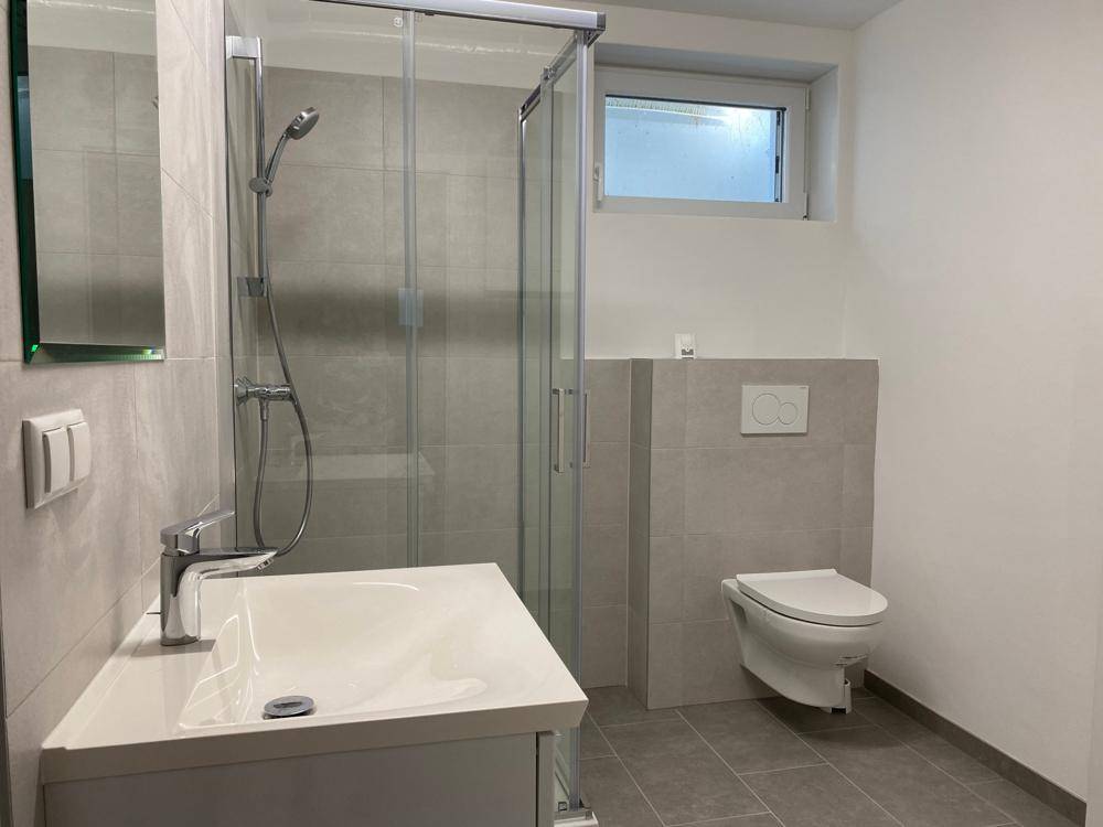 Modernes Badezimmer im Untergeschoss mit Dusche, Waschbecken und WC.