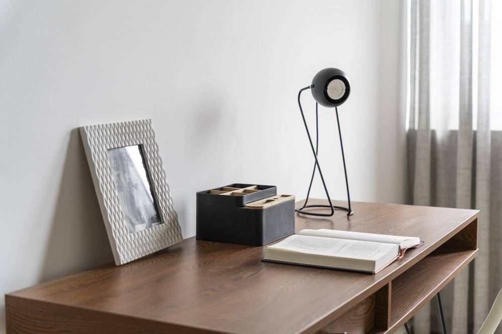 Heller Arbeitsbereich mit modernem Holzschreibtisch, minimalistischer Lampe und Fenster mit Vorhängen.