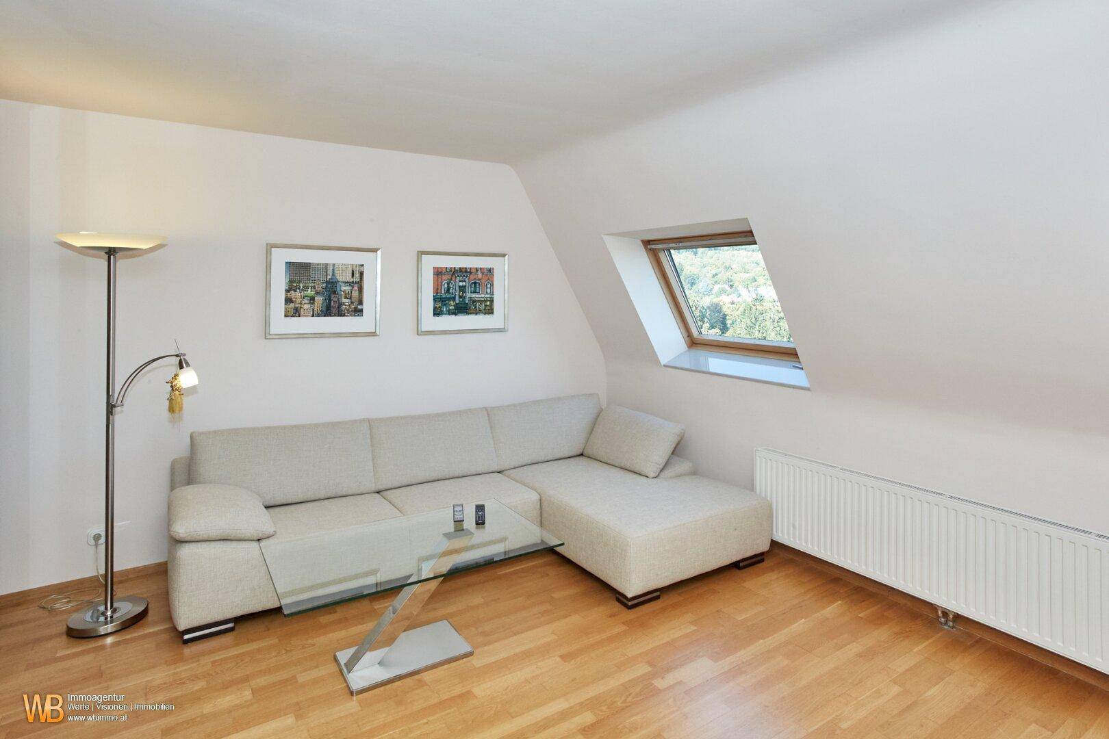 Gemütliches Wohnzimmer im Dachgeschoss mit Schrägdach, Dachfenster und hellem Holzboden.
