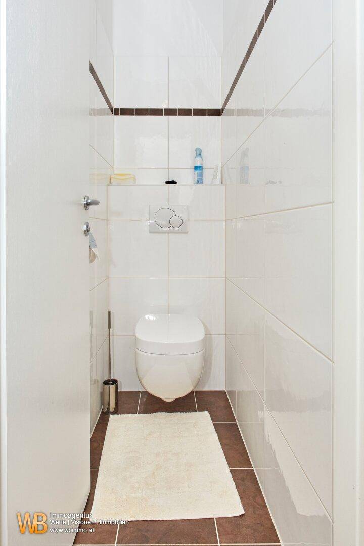 Kleines Gäste-WC mit Wand-WC, Fliesenboden und schlichter, funktionaler Gestaltung.