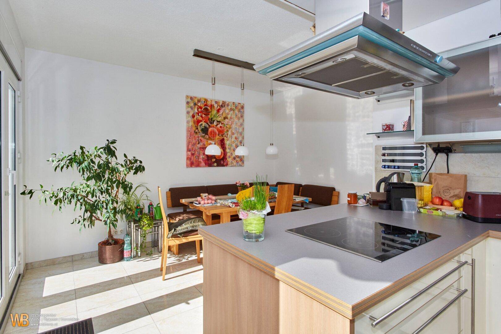 Geräumige Wohnküche mit Essbereich, Kücheninsel und hellem Fliesenboden, ideal für Familien.
