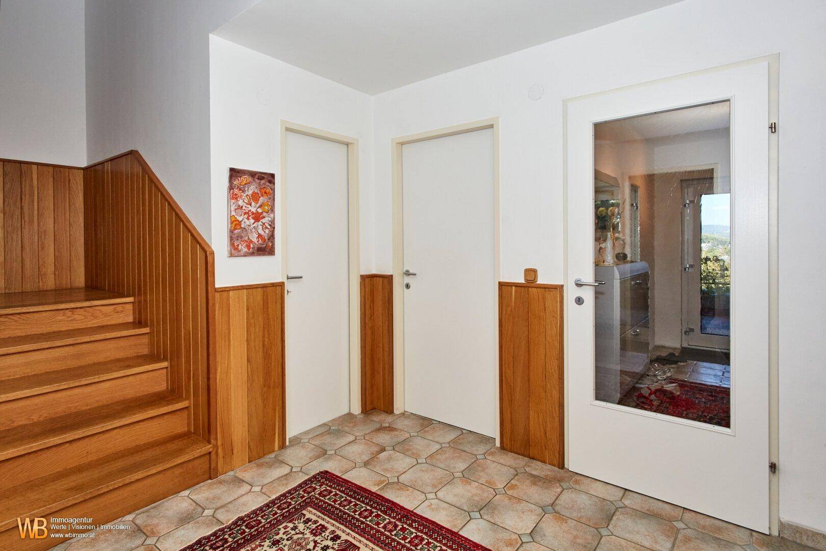 Heller Flur mit Fliesenboden, Holzakzenten und Türen zu verschiedenen Räumen.
